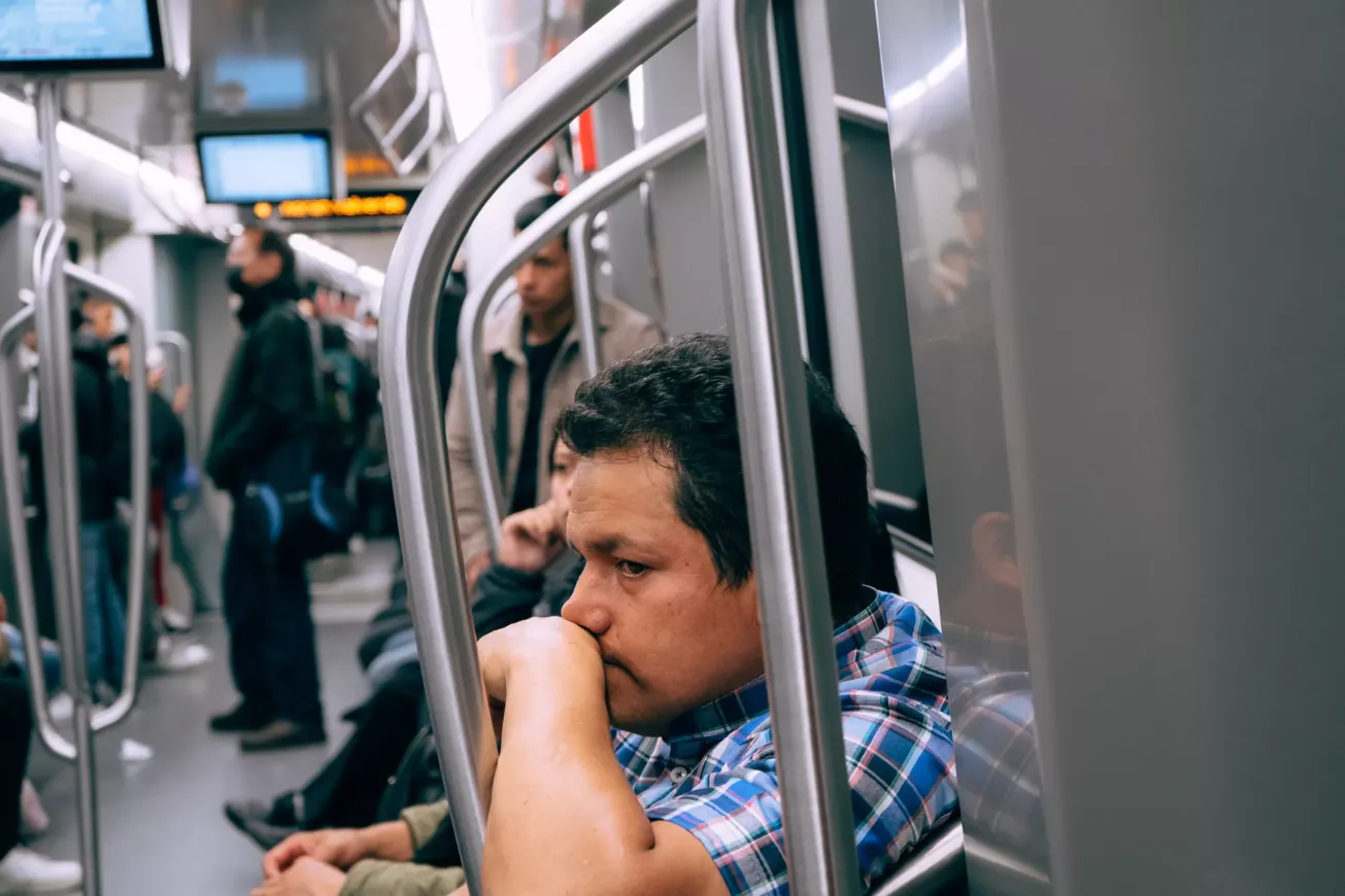 Hombre cansado espera su parada para bajarse en el metro de Quito Hombre cansado espera su parada para bajarse en el metro de Quito