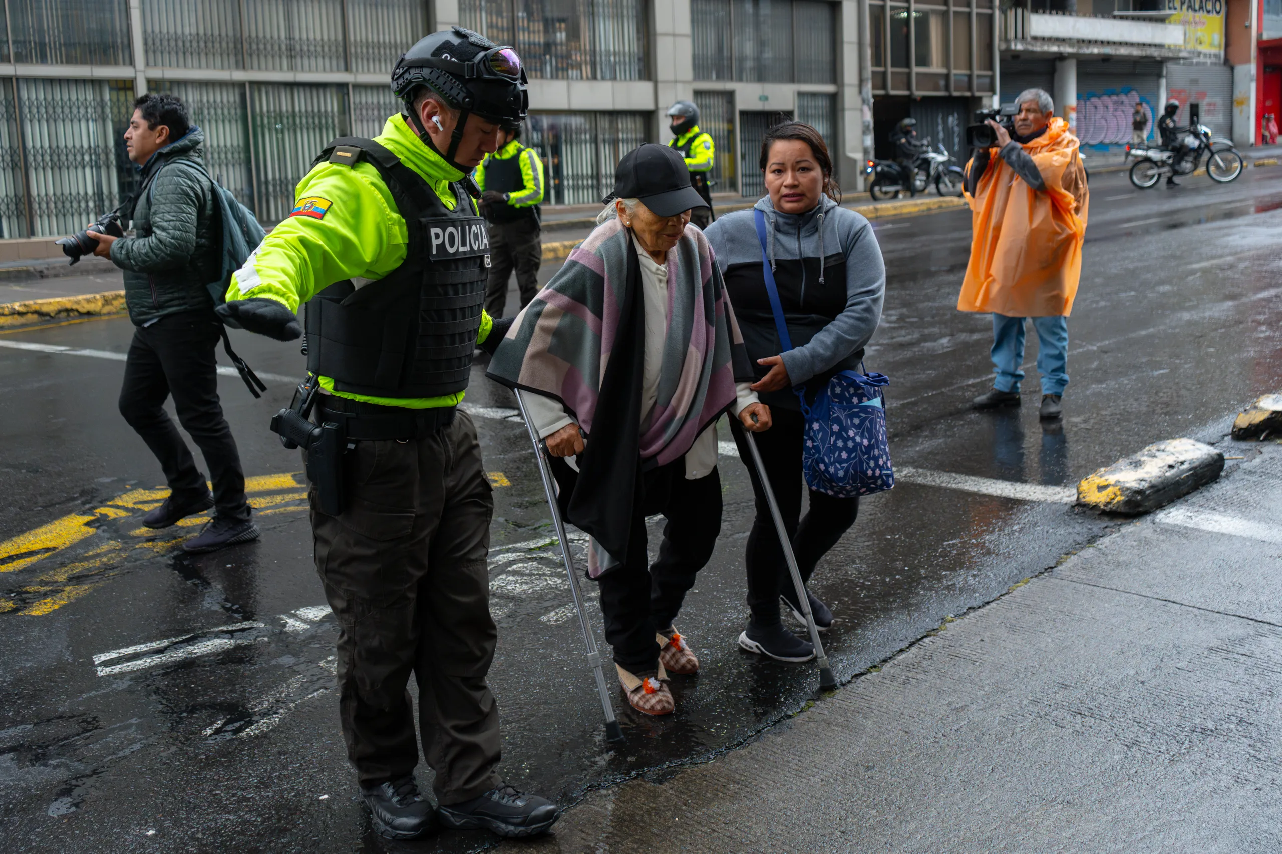 Un policía y una manifestante ayudan a cruzar la calle a una anciana en una protesta en Quito. Un policía y una manifestante ayudan a cruzar la calle a una anciana en una protesta en Quito.